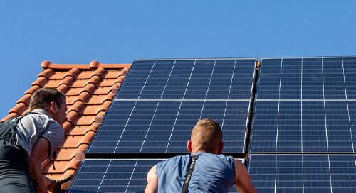 Two men on a roof installing solar panels
