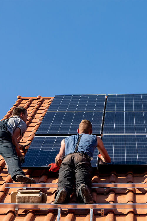 Two men on a roof installing solar panels