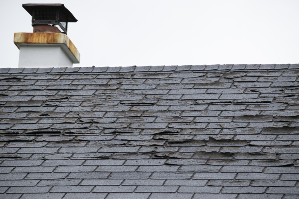 Close up of a roof with damaged shingles coming off