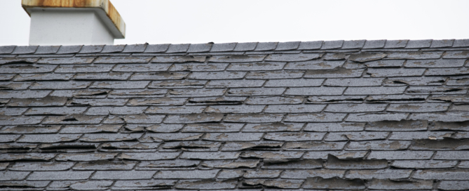 Close up of a roof with damaged shingles coming off