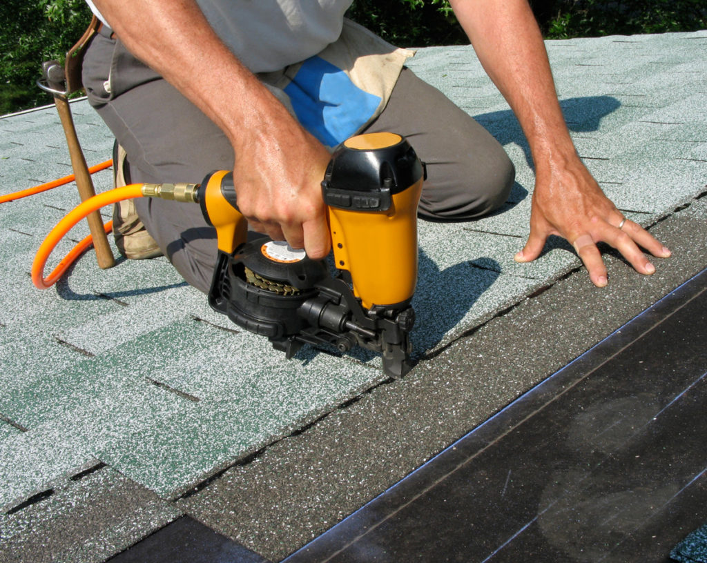Worker installing roofing shingles