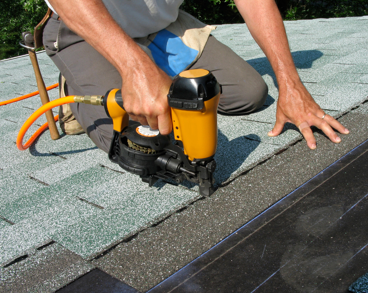 Worker installing roofing shingles