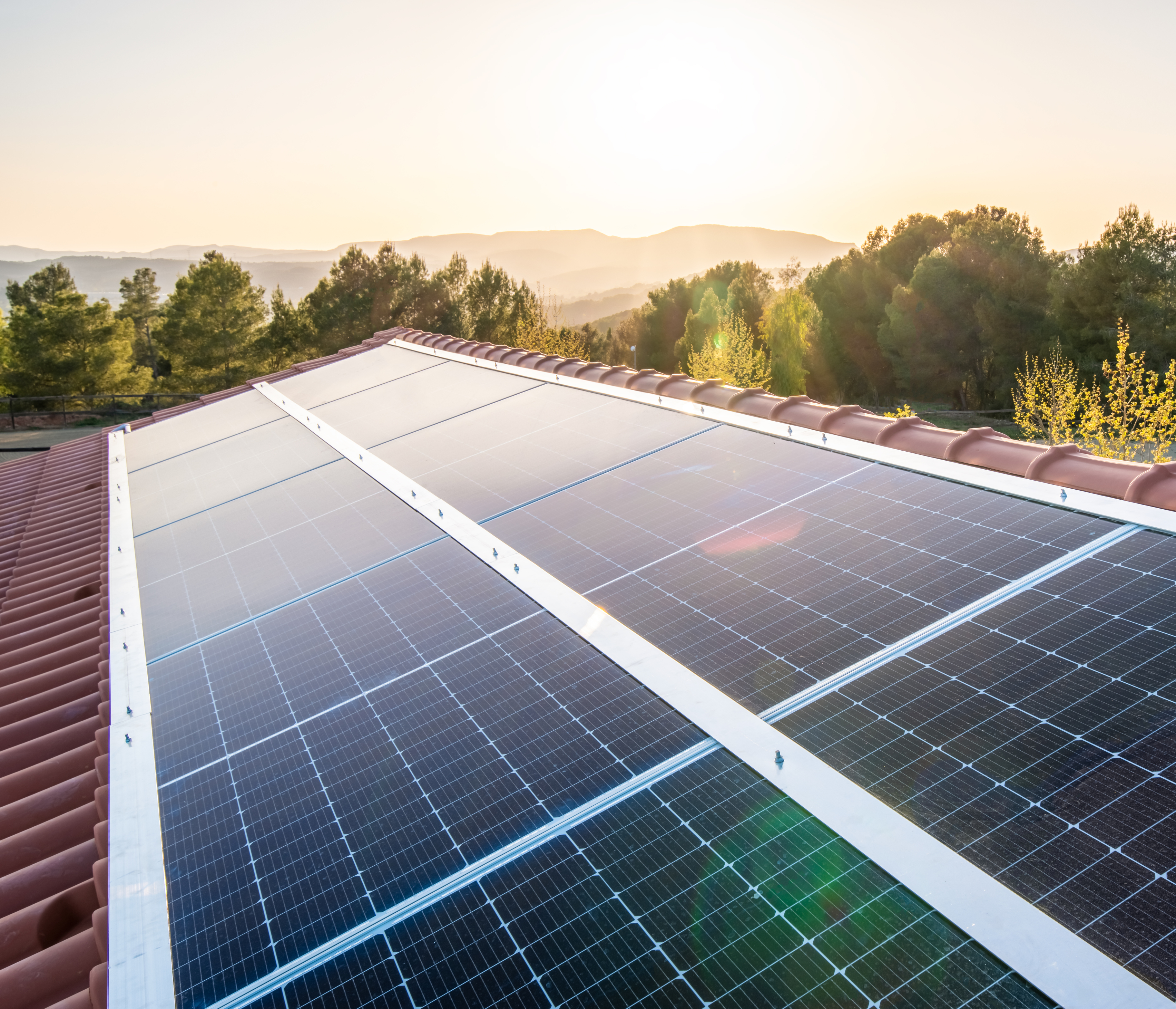 solar panels on roof with the sun setting