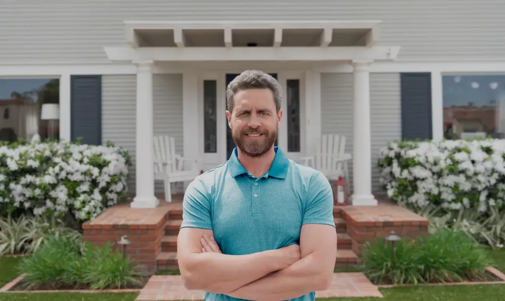 A happy man standing outside of his home after getting solar panels installed.